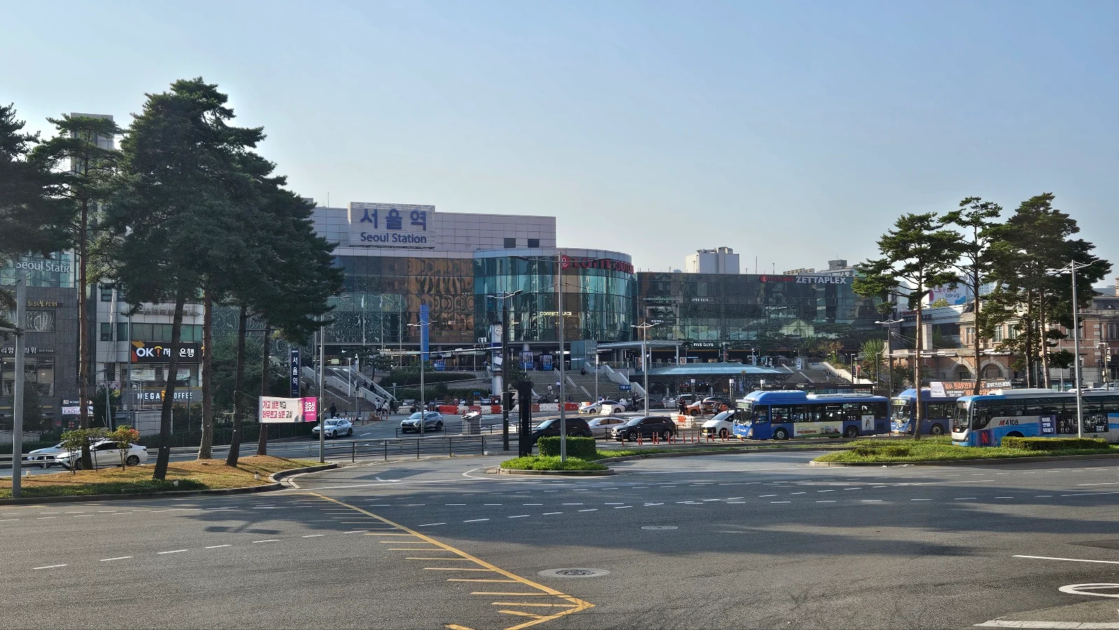 Street-level view across the road toward the main Seoul Station building and bus stops